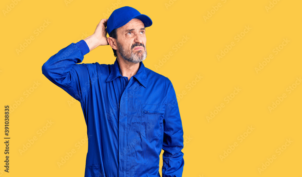 Middle age handsome man wearing mechanic uniform confuse and wondering about question. uncertain with doubt, thinking with hand on head. pensive concept.