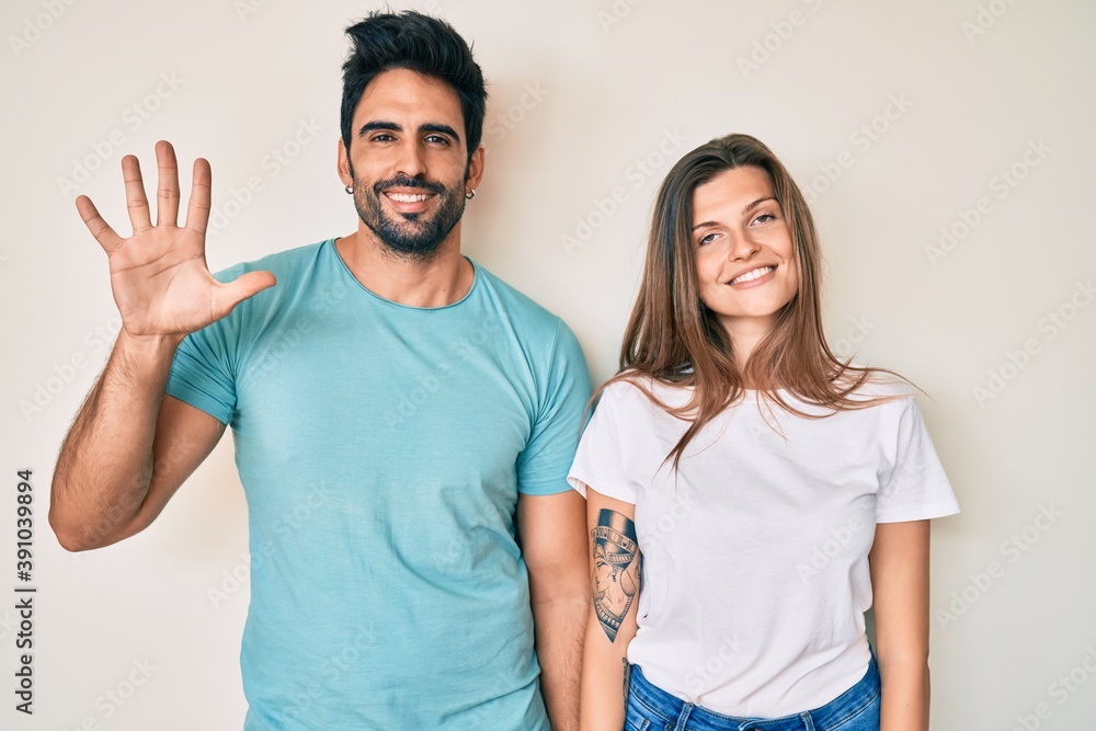 Beautiful young couple of boyfriend and girlfriend together showing and pointing up with fingers number five while smiling confident and happy.