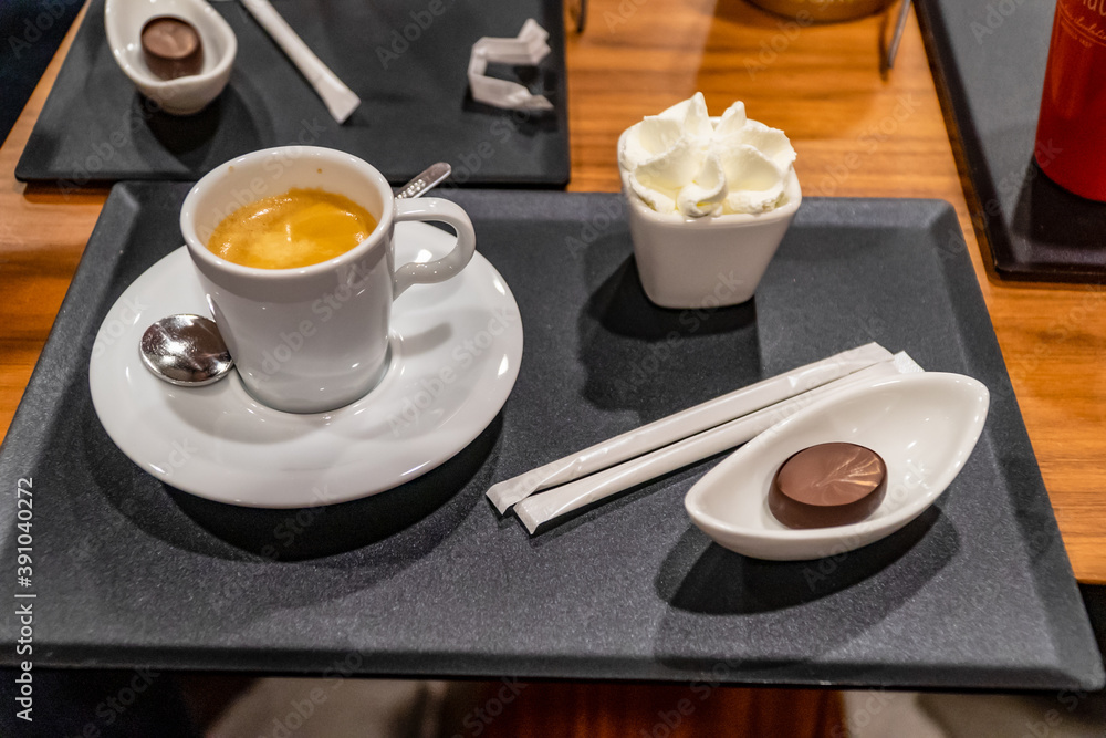 cup of coffee, brownie and small jar of whipped cream, laid out on a black table cup of coffee, brownie and small jar of whipped cream, laid out on a black table