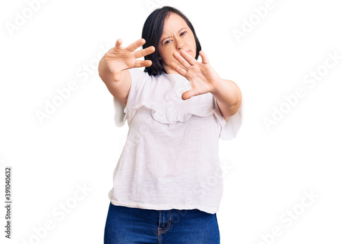 Brunette woman with down syndrome wearing casual white tshirt doing frame using hands palms and fingers, camera perspective