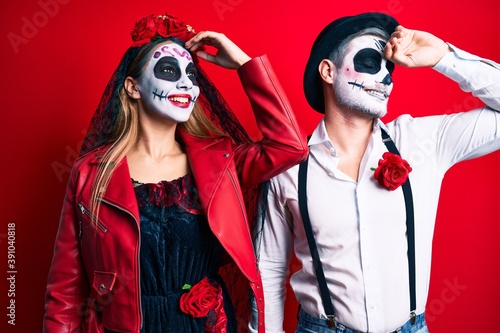 Couple wearing day of the dead costume over red smiling confident touching hair with hand up gesture  posing attractive and fashionable