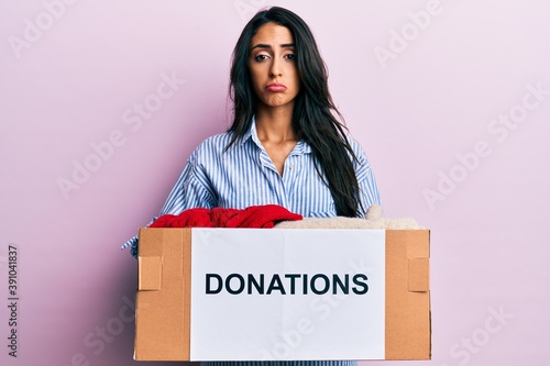 Beautiful hispanic woman volunteer holding donations box depressed and worry for distress, crying angry and afraid. sad expression. © Krakenimages.com