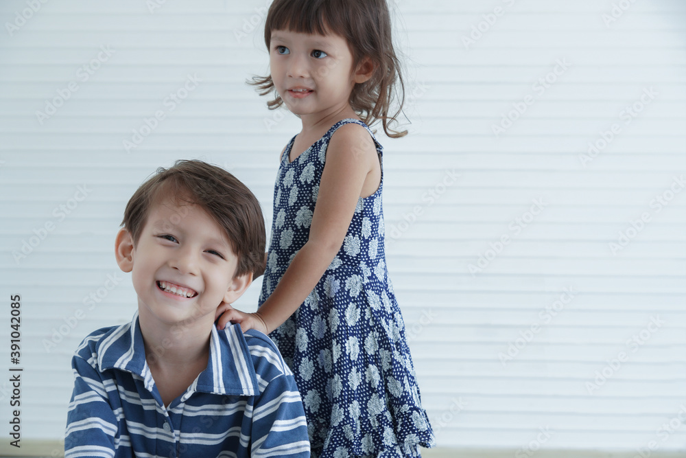 Little Caucasian boy and girl sitting and smile together at home. Happy siblings brother and sister spend time together on white background Little Caucasian boy and girl sitting and smile together at home. Happy siblings brother and sister spend time together on white background