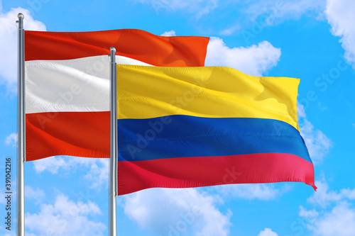 Colombia and Austria national flag waving in the windy deep blue sky. Diplomacy and international relations concept.