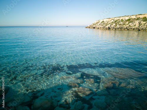 Cristal clear water and no people at the famous Cala Azzurra in Favignana, Italy. A perfect calm sunrise in this paradise island in the mediterranean sea