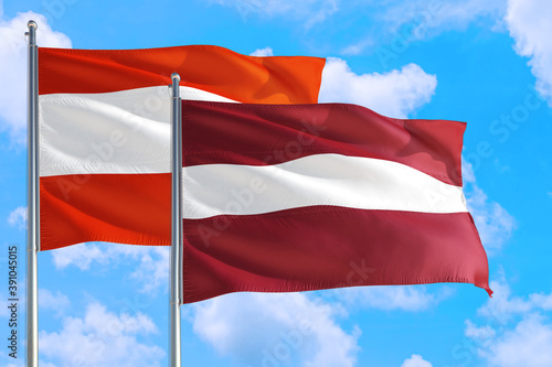 Latvia and Austria national flag waving in the windy deep blue sky. Diplomacy and international relations concept.
