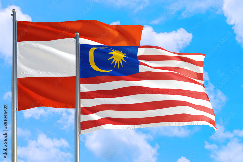Obraz premium Malaysia and Austria national flag waving in the windy deep blue sky. Diplomacy and international relations concept.