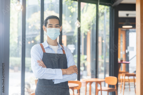 portrait waiter in café, coffee shop staff, smart Asian man wearing mask and cross arm
