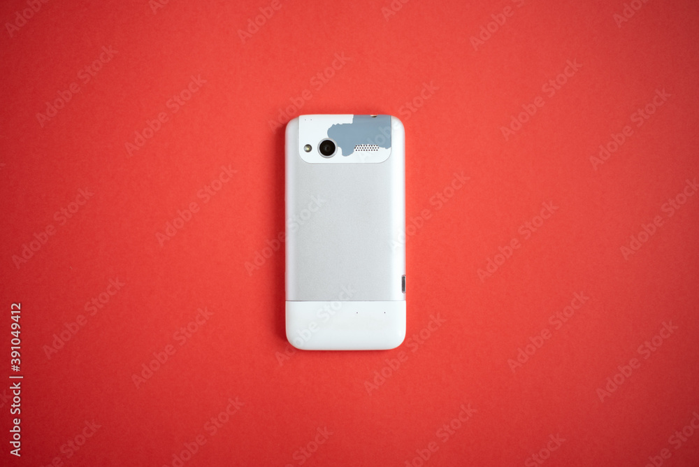 Old, outdated and worn cell phone on a red background. Old, outdated and worn cell phone on a red background.