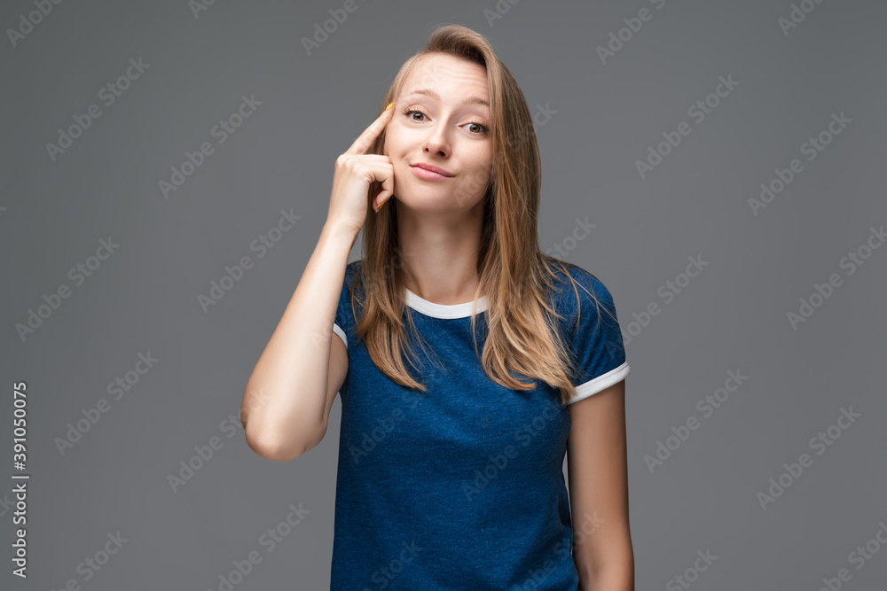 Studio shot of Confident young female pointing with finger at head. Concept of thinking. Be smart and think Studio shot of Confident young female pointing with finger at head. Concept of thinking. Be smart and think