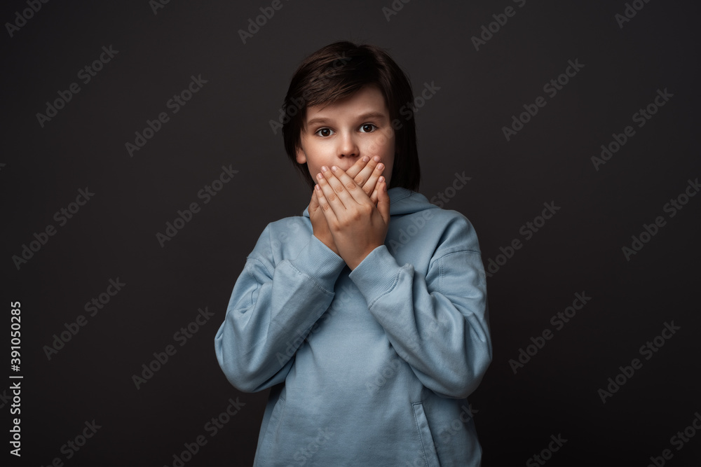 Image of scared boy covering his mouth with hands. Fright, phobia and facial expression concept Image of scared boy covering his mouth with hands. Fright, phobia and facial expression concept