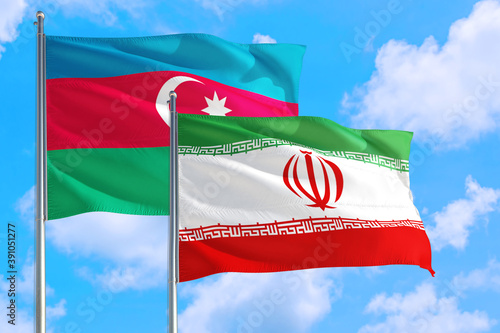 Iran and Azerbaijan national flag waving in the windy deep blue sky. Diplomacy and international relations concept.