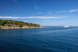 Agios Nikolaus coastline on a sunny day with clear turquoise sea and cliffs. Crete, Greece, Aegean Sea.