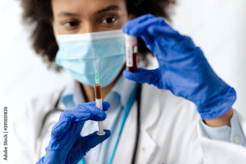 Close-up of doctor holding syringe and blood test sample at medical clinic. Close-up of doctor holding syringe and blood test sample at medical clinic.
