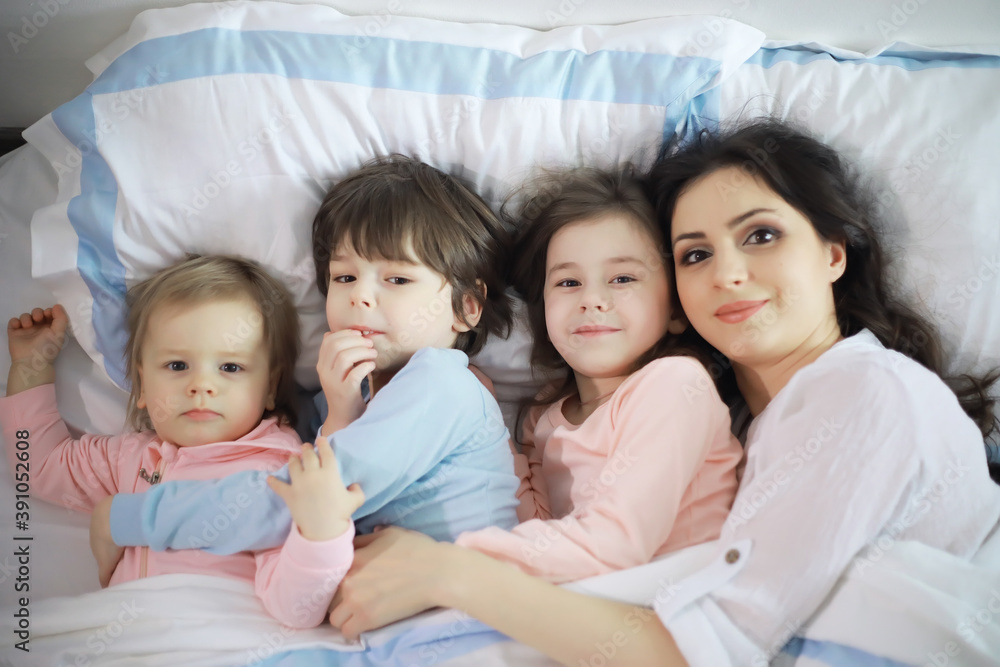 A family with children having fun on the bed under the covers during the Christmas holidays. A family with children having fun on the bed under the covers during the Christmas holidays.
