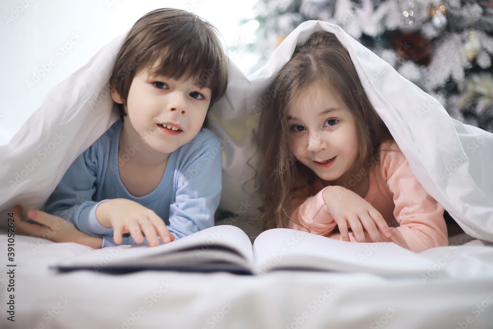 A family with children having fun on the bed under the covers during the Christmas holidays.