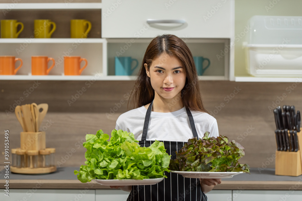 Happy young Asian woman cooking with fresh vegetable in the modern kitchen