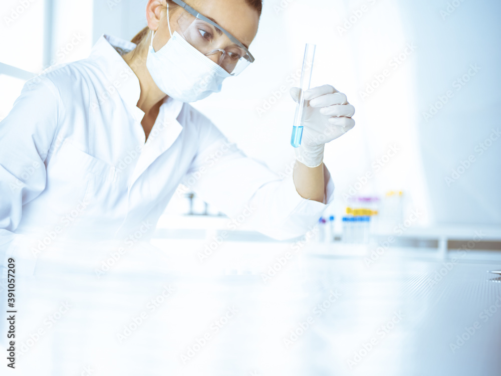 Female laboratory assistant analyzing test tube with blue liquid. Medicine, health care and researching concept Female laboratory assistant analyzing test tube with blue liquid. Medicine, health care and researching concept