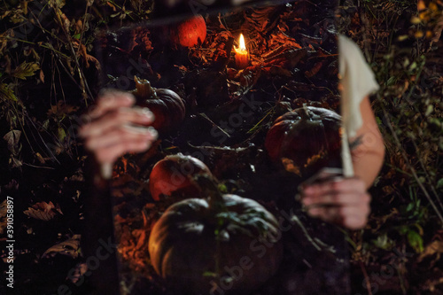 Pumpkins and candles, reflected in the mirror in the hands of the model. Dark Halloween background for the site.
