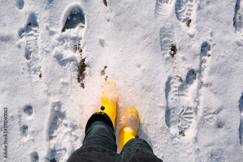 Winter walk in yellow rubber boots on fresh snow. Kicks up loose snow. Sunny frosty weather in the fresh air. Top view