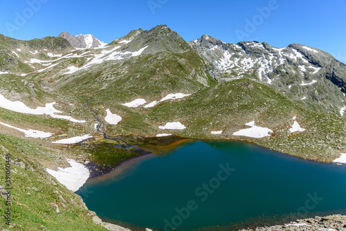 Wild lake Southtirol Italia Val pusteria Alpine pastures with a deep blue lake, green meadows and a blue sky with fleecy clouds, in summer