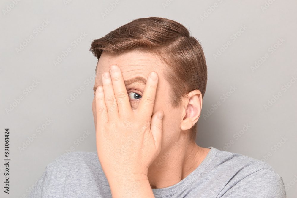 Portrait of man covering face and looking through fingers at something Portrait of man covering face and looking through fingers at something