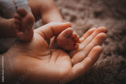 legs of a newborn in the hands of a parent