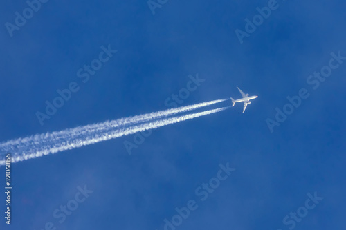 Airplanes leaving contrail trace turns in a clear blue sky. © aapsky