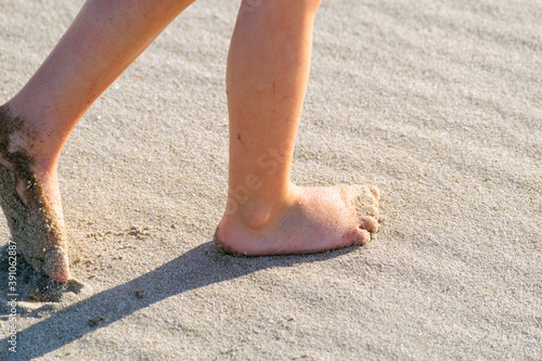 Boy dragging toe through sand
