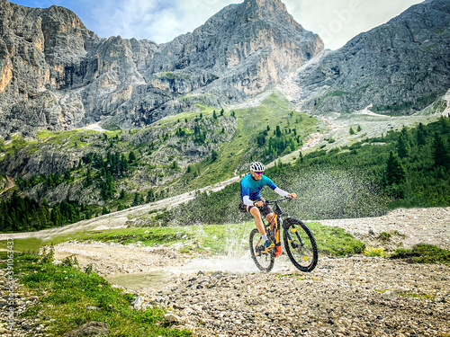 Man doing mountain biking in a mountain route - Sport Man riding a mountain bike passes in through a shallow stream running through tranquil nature