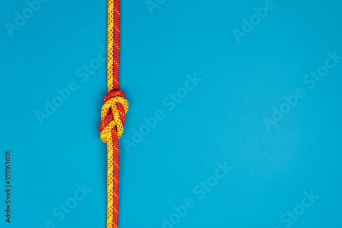 Figure-eight knot with red and yellow climbing ropes on blue background