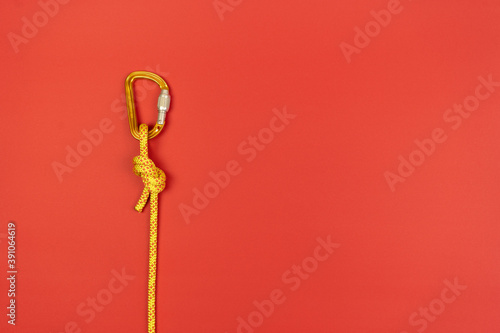 Overhand knot with orange carabiner and yellow climbing rope on red background