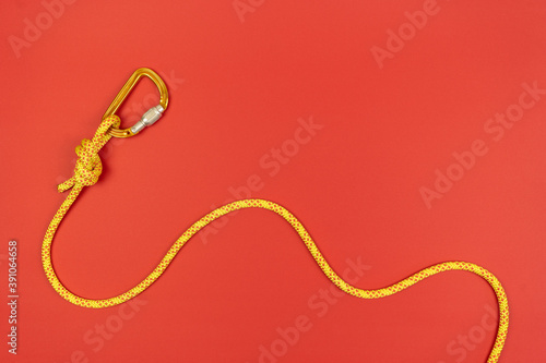 Foto Overhand knot with orange carabiner and yellow climbing rope on red background