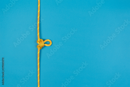 Butterfly loop knot with yellow climbing rope on blue background