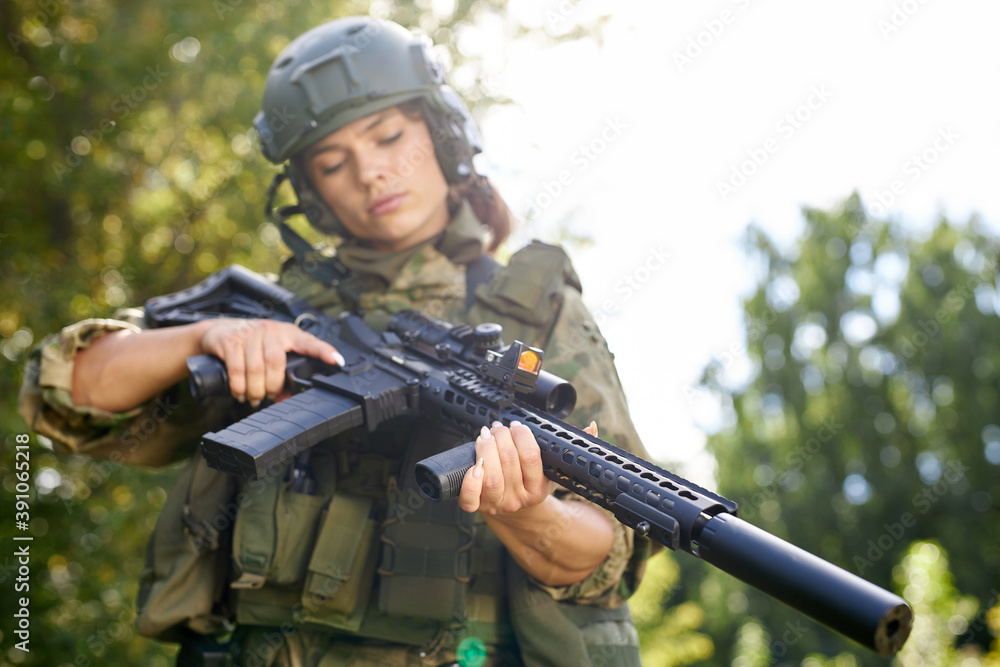 young caucasian military woman is checking rifle in the forest before shooting, alone in nature, female soldier young caucasian military woman is checking rifle in the forest before shooting, alone in nature, female soldier
