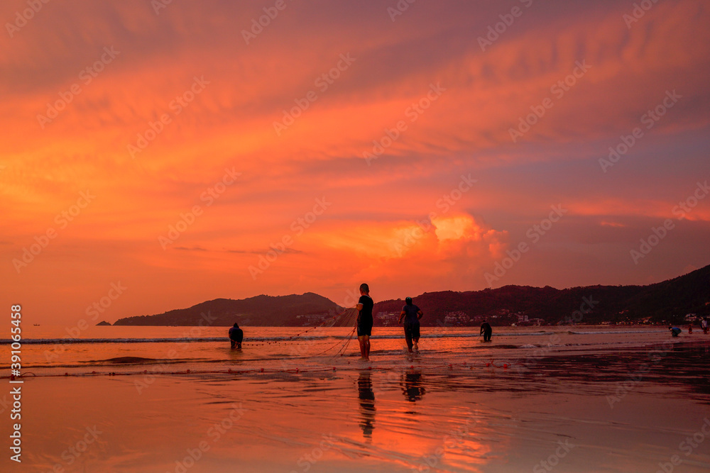 .People come out to trawl their nets on Patong beach during sunset time..