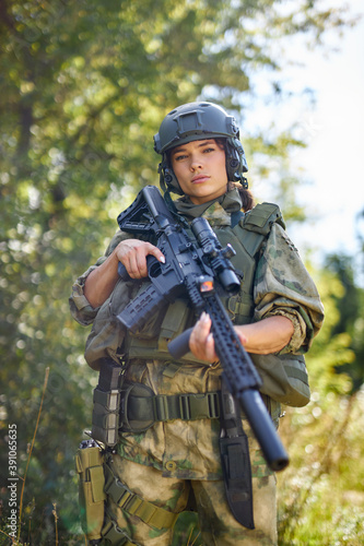 strong brave female army soldier with rifle machine gun standing in the forest, she is ready to shoot at enemy, firearm outdoor shooting range
