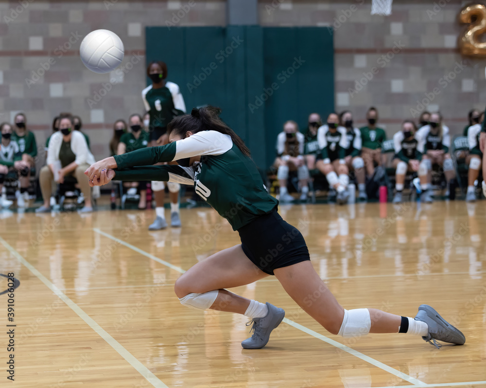 Girl volleyball players blocking and hitting the ball during a game