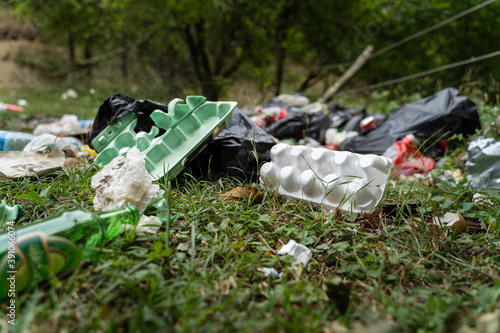 Fotografie Pollution in nature - garbage thrown on the field covering grass - trash in the