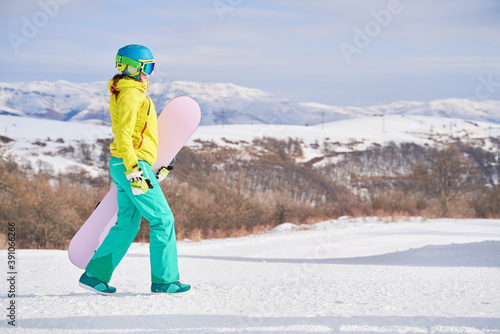 Woman with snowboard against background of mountains