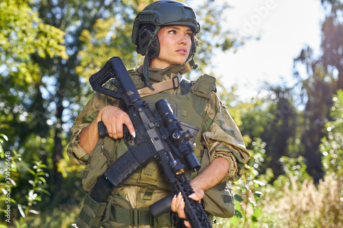 attractive brave military woman with a gun in forest, survival in wild forest, caucasian female in green suit camouflage suit with rifle or weapon