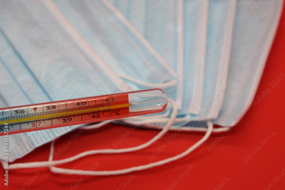 medical protective masks and mercury thermometer on a red background medical protective masks and mercury thermometer on a red background