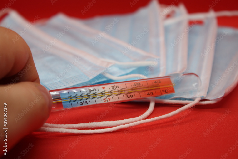 medical protective masks and mercury thermometer on a red background medical protective masks and mercury thermometer on a red background