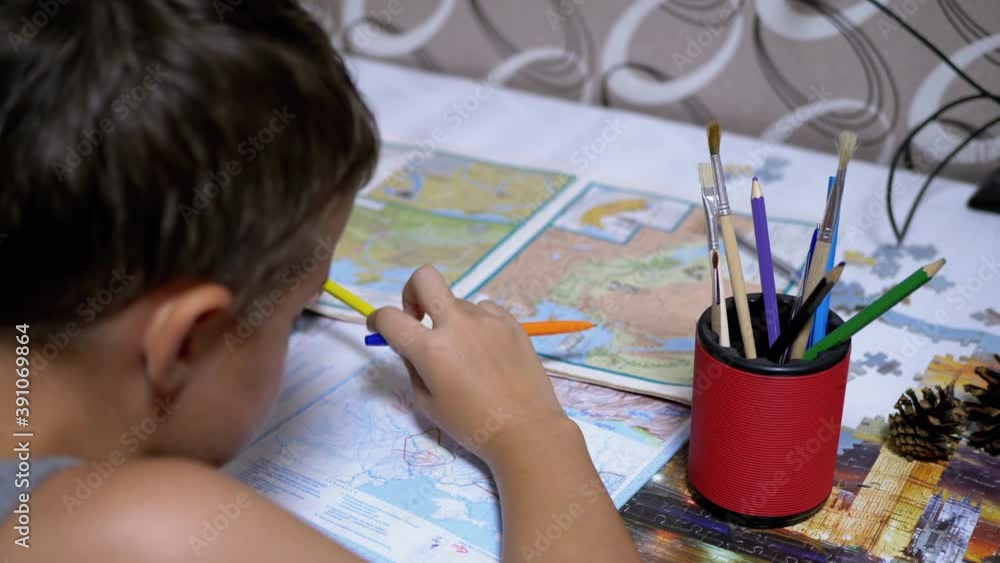 Schoolboy is Studying Map holding Pen and Pencil in Hand. Online Homeschooling Schoolboy is Studying Map holding Pen and Pencil in Hand. Online Homeschooling