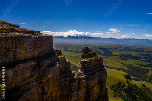 An excellent view from the plateau to the extinct volcano and the snowy peak of Mount Elbrus. Below is a green gorge