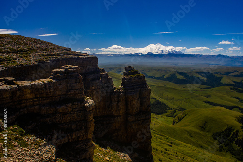 An excellent view from the plateau to the extinct volcano and the snowy peak of Mount Elbrus. Below is a green gorge