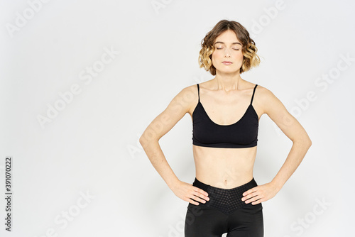 Slender girl in sportswear on a light background leggings hairstyle cropped view © SHOTPRIME STUDIO