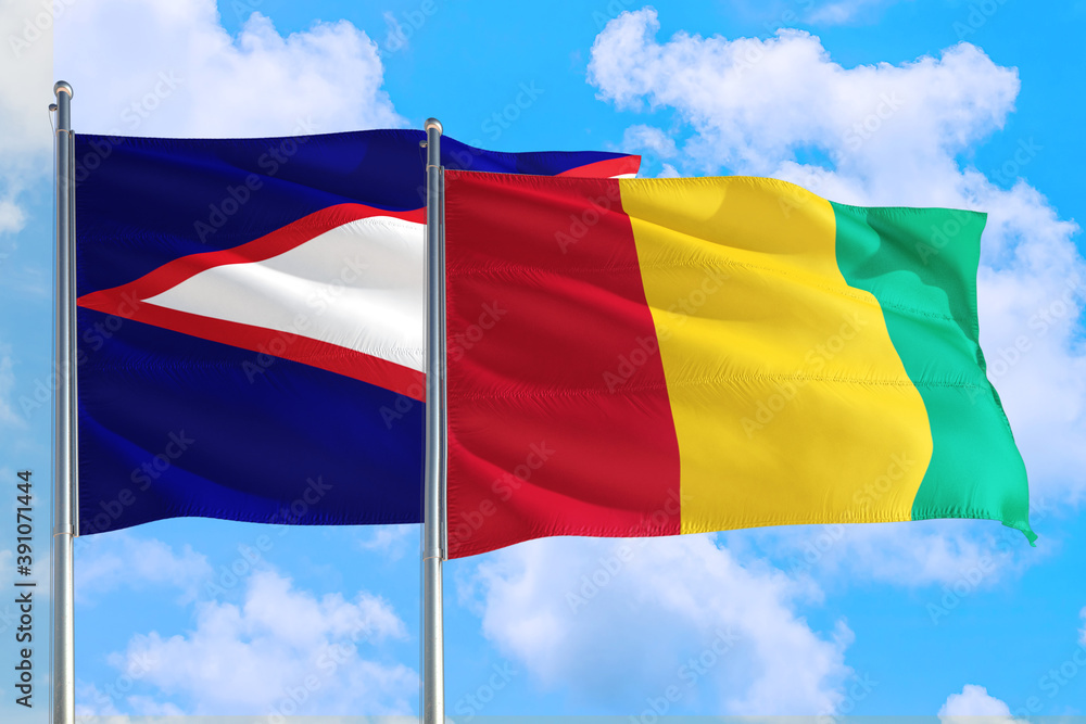 Guinea Bissau and American Samoa national flag waving in the windy deep blue sky. Diplomacy and international relations concept. Guinea Bissau and American Samoa national flag waving in the windy deep blue sky. Diplomacy and international relations concept.