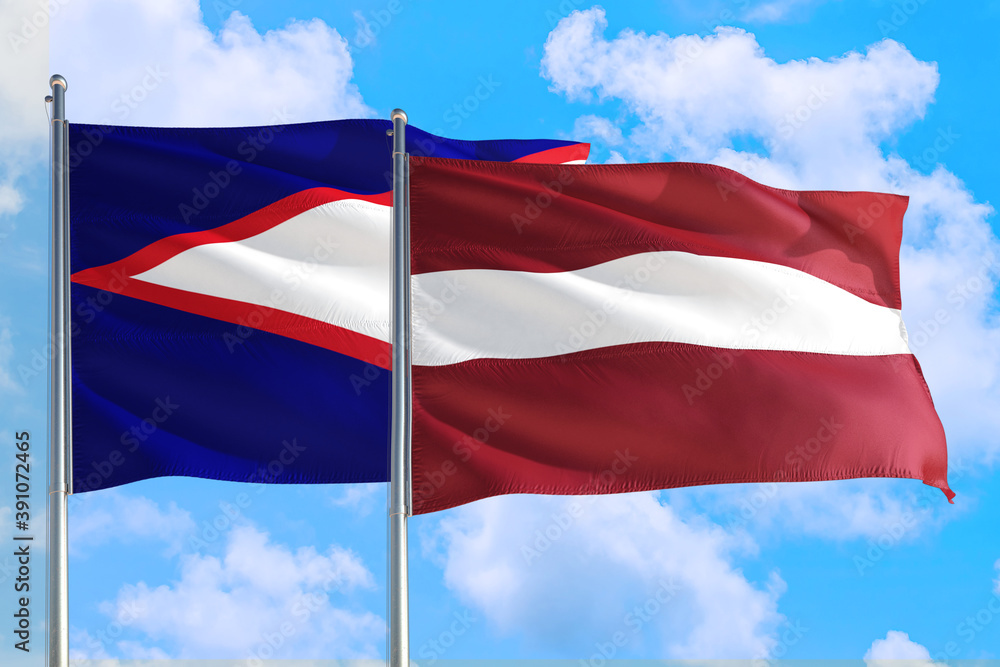 Latvia and American Samoa national flag waving in the windy deep blue sky. Diplomacy and international relations concept. Latvia and American Samoa national flag waving in the windy deep blue sky. Diplomacy and international relations concept.