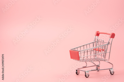 Shopping concept - Red shopping cart on pink background with copy space.